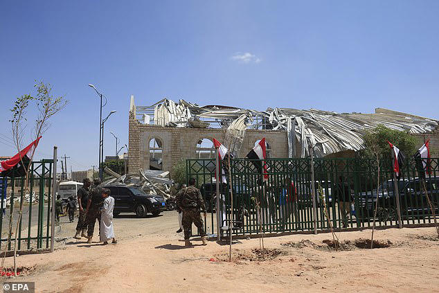 Houthi soldiers stand guard next to a sports hall building targeted by a previous Saudi-led airstrike, in Sanaa, Yemen, on October 3